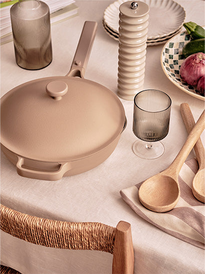 Beige saucepan on a table with cooking utensils